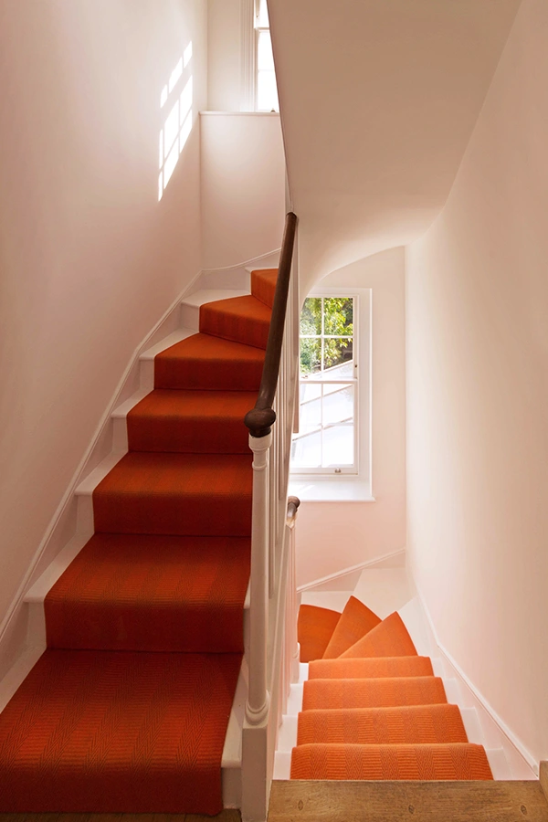 orange runner on stairs with sash window behind