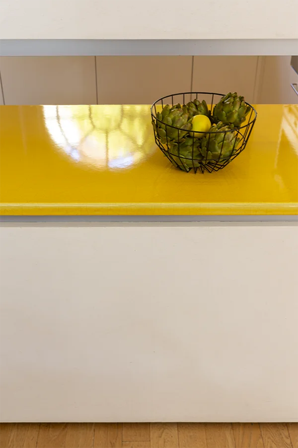 detail of enameled yellow kitchen counter with fruit bowl