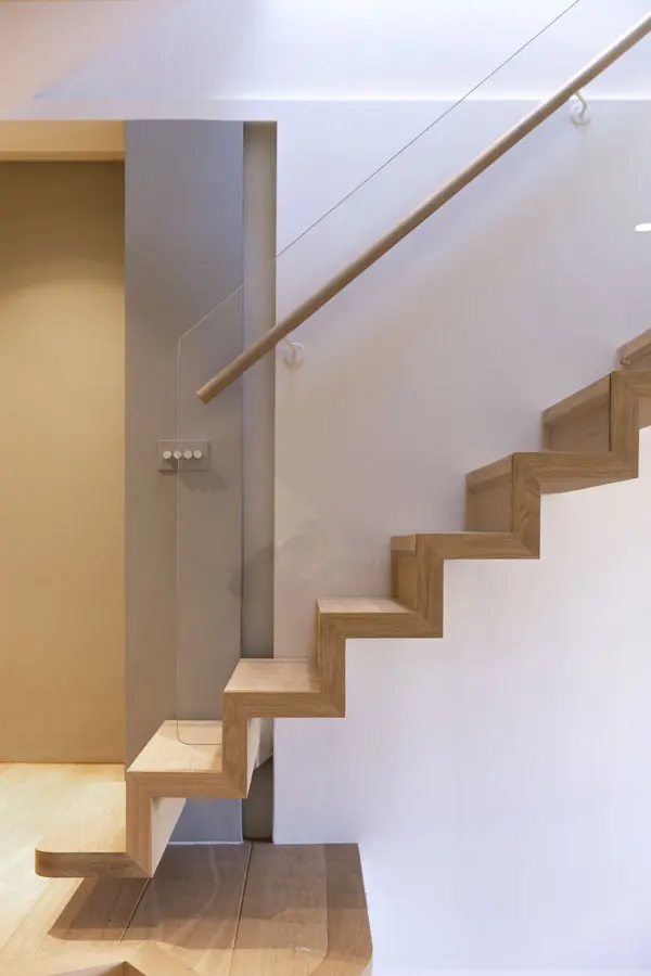 Side view of cantilevered oak stair, with transparent glass balustrade