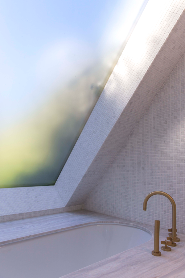 Sunken bath below rooflight, with stone mosaic