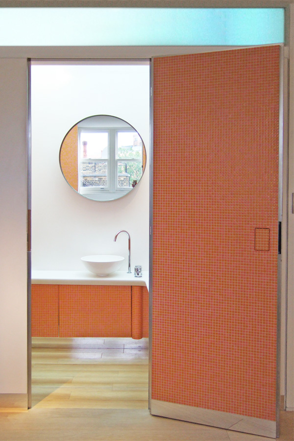 Vibrant terracotta orange mosaic enveloping the children's bathroom furniture