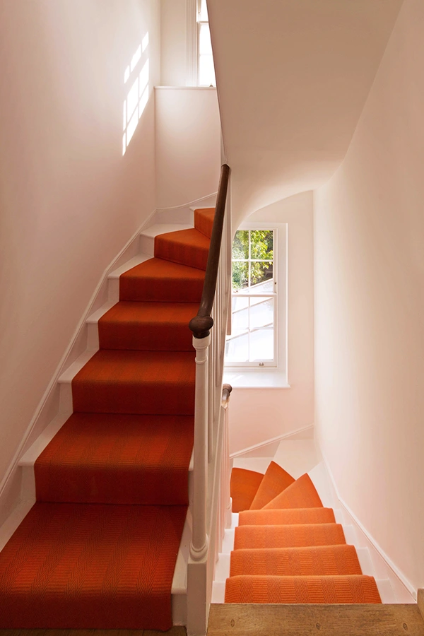 Orange runner on stairs with sash window behind