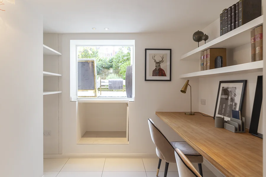 Desk and shelving in basement study with garden beyond
