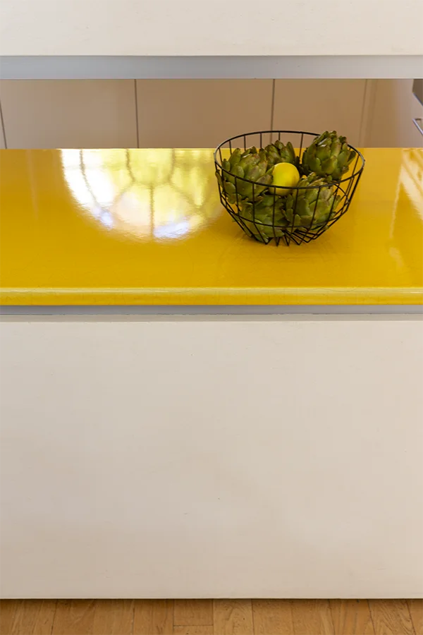 Detail of enameled yellow kitchen counter with fruit bowl