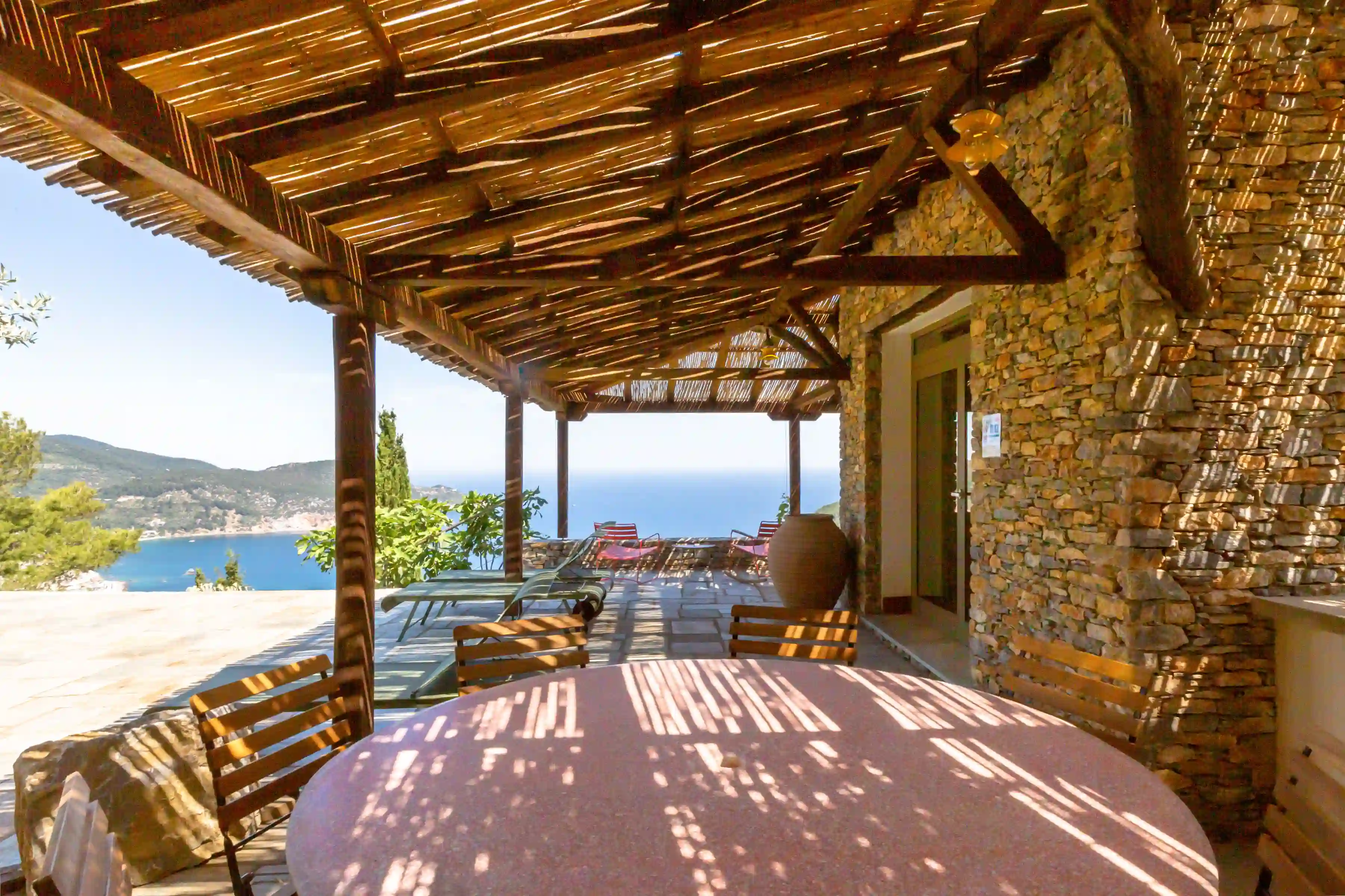 View towards Skopelos bay from the main poolside terrace circular dining table, beneath the wooden pergola