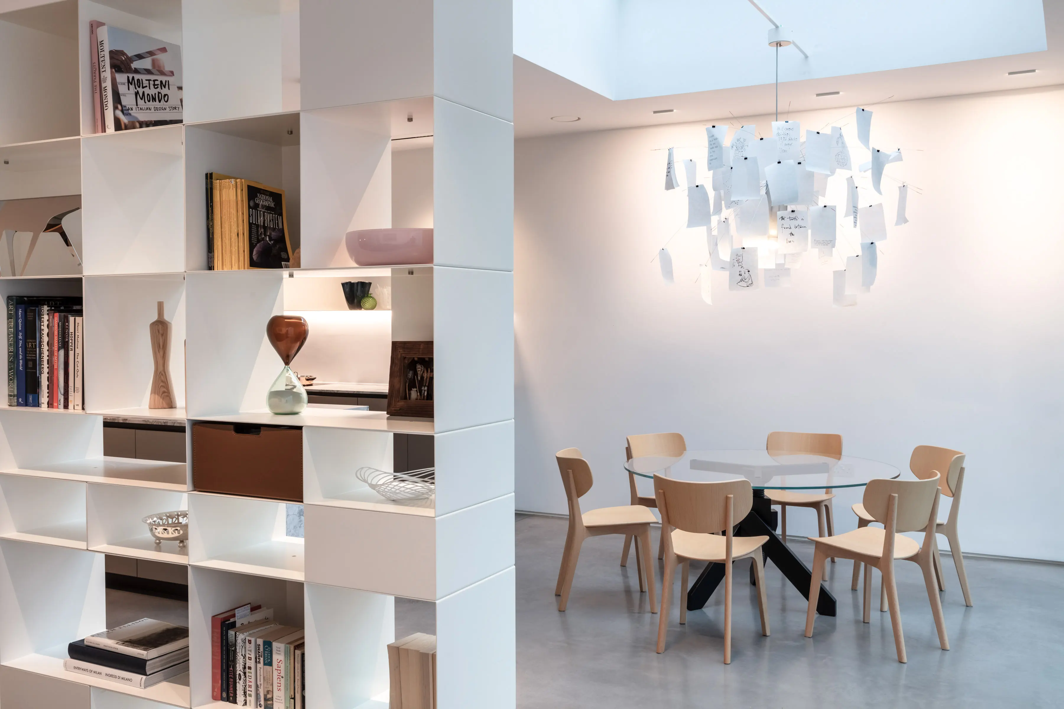 New ground-floor extension at Staverton Road Oxford — dining area with round glass table, Flos pendant light viewed from the bookcase