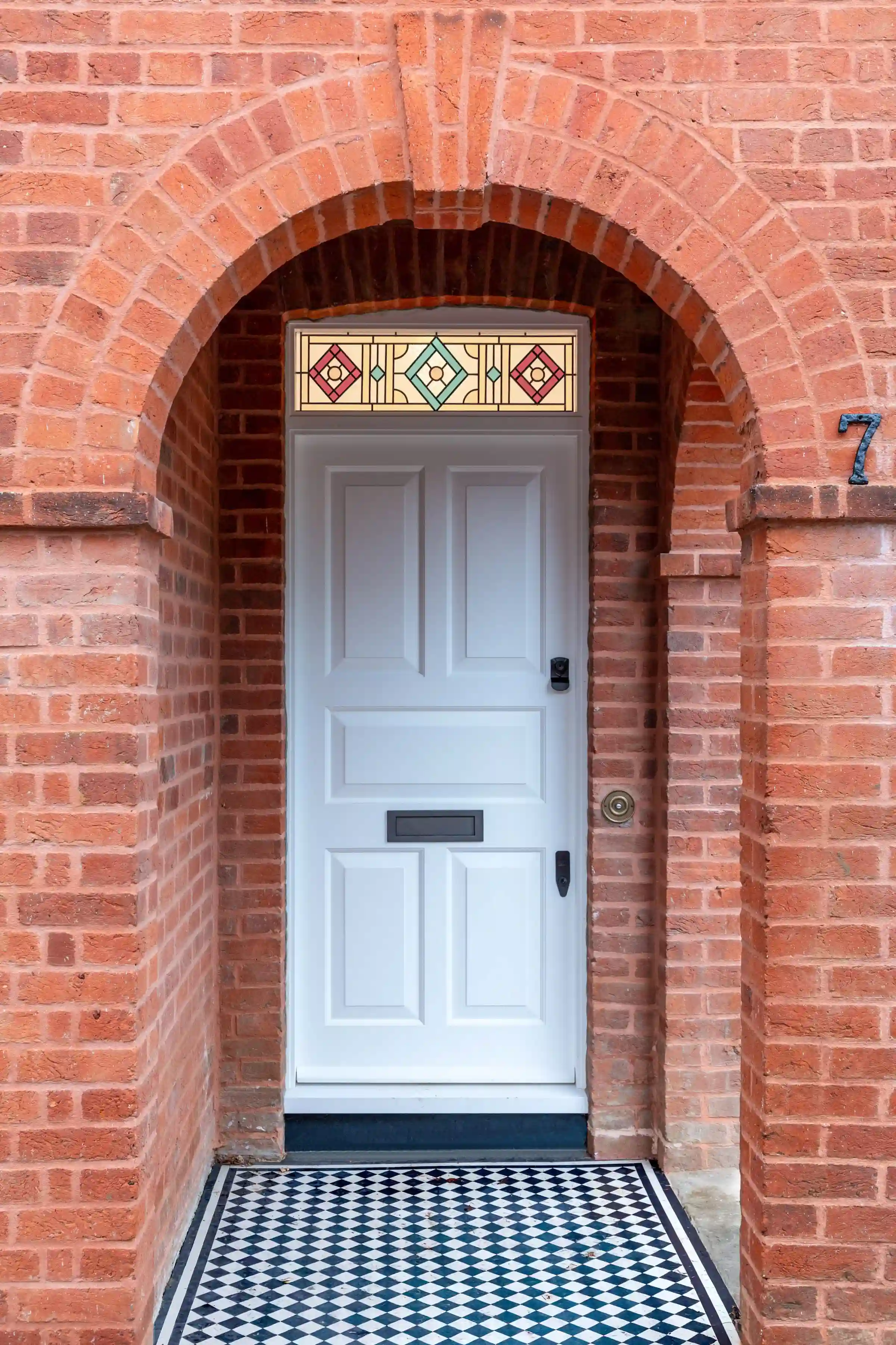 Front entrance at Staverton Road Oxford — the brick porch and white front door with stained glass light above