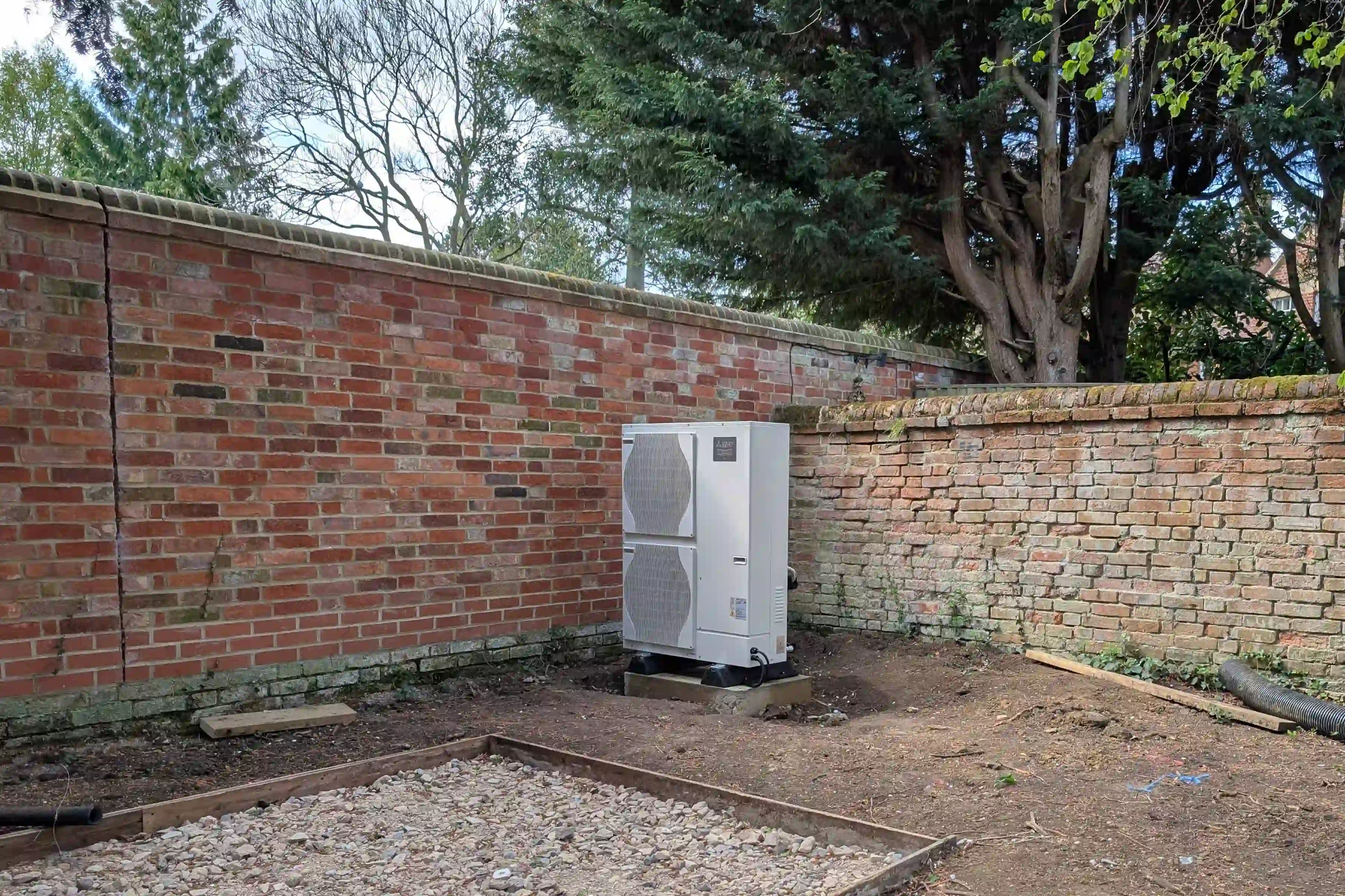 The new air source heat pump being installed at the back of the garden